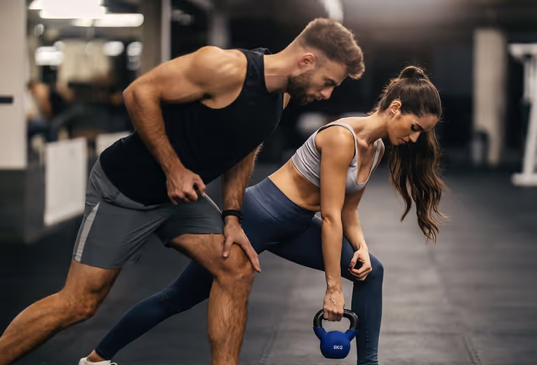 Personal trainer showing the client how to do the workout the correct way with proper form